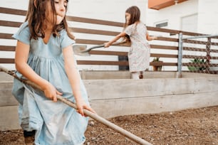 a little girl holding a shovel and a little girl holding a stick