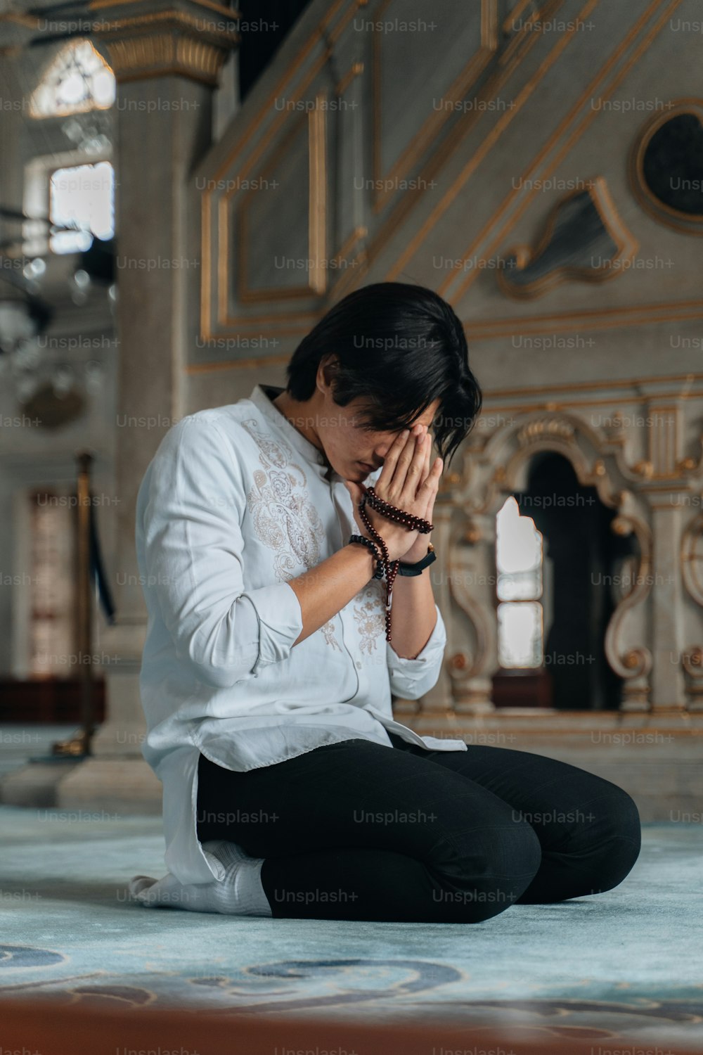 a woman sitting on the floor covering her face with her hands