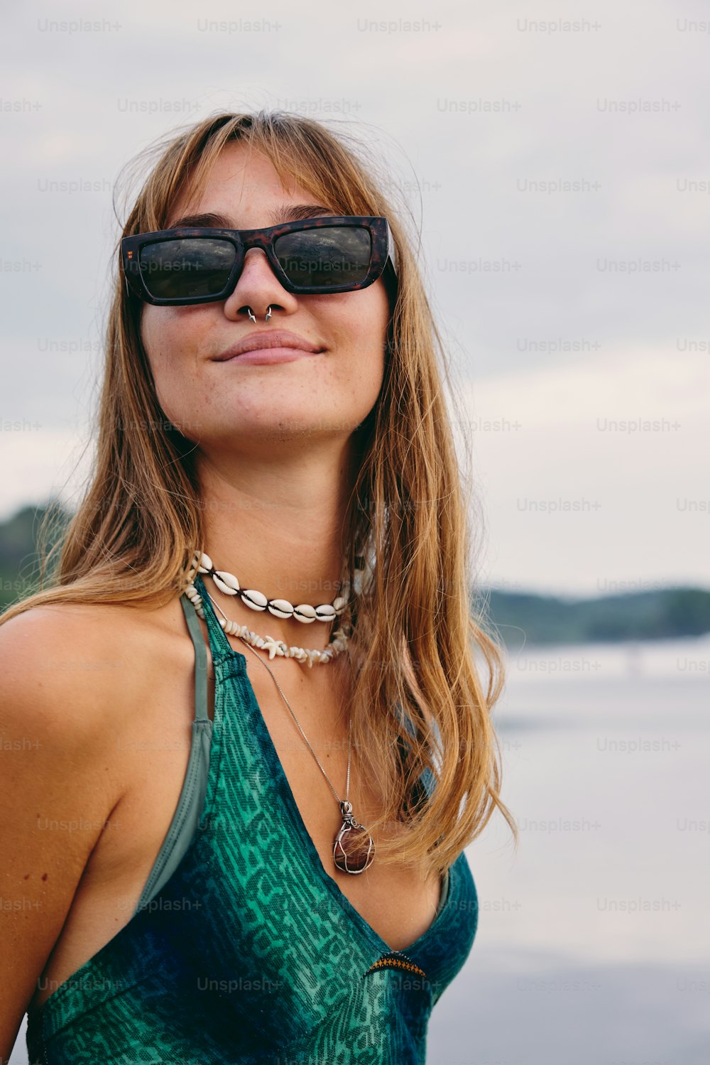 a woman wearing sunglasses standing next to a body of water
