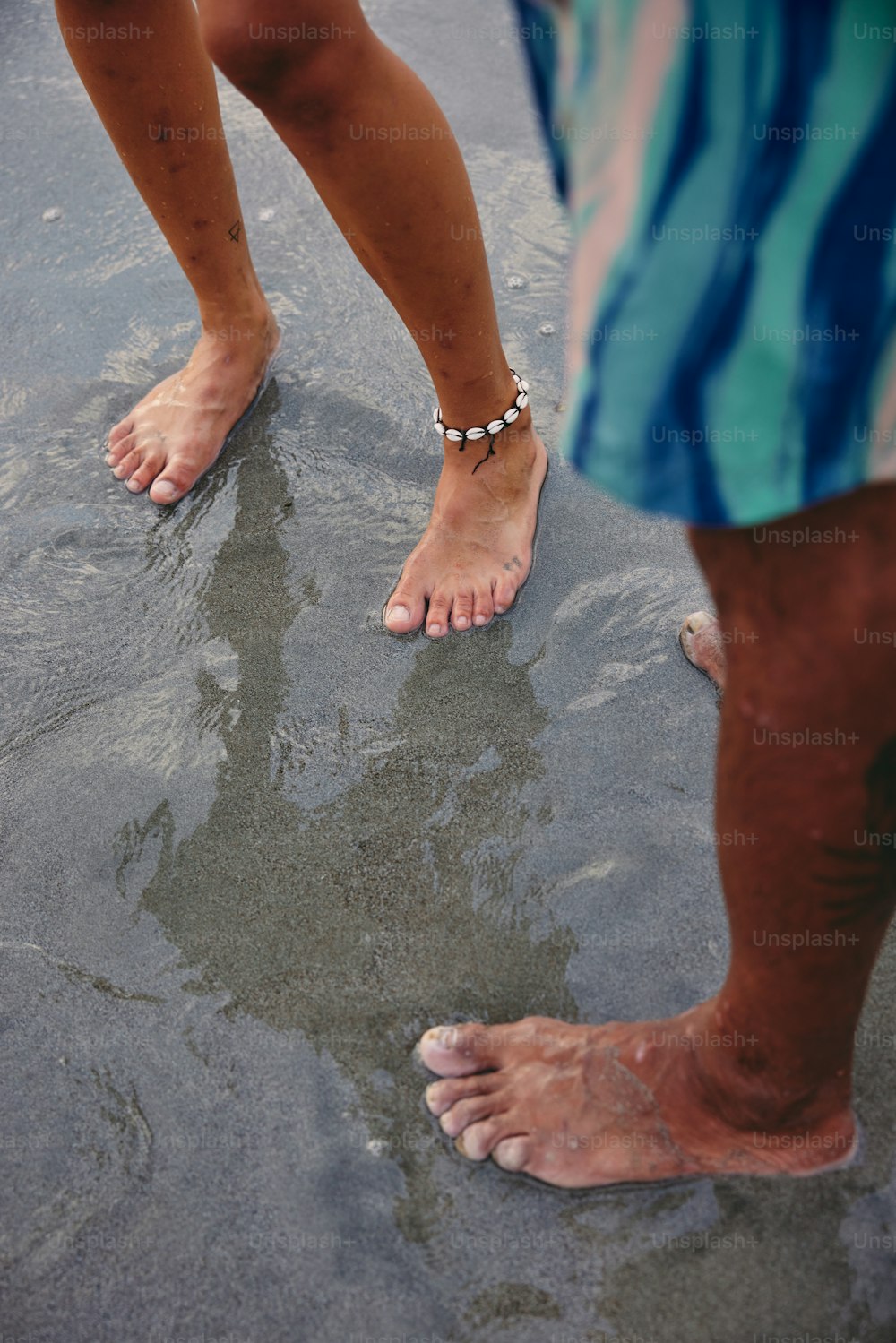 un paio di persone in piedi sulla cima di una spiaggia bagnata