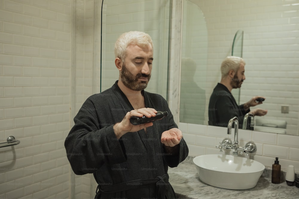 a man in a robe holding a remote control in a bathroom