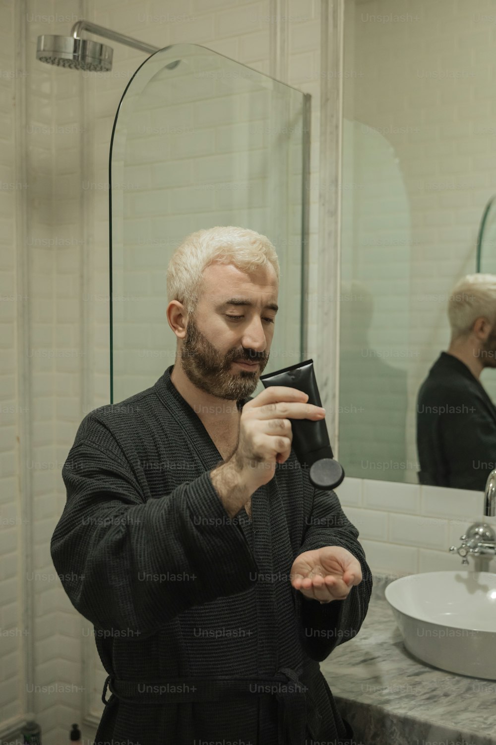 Ein Mann im Bademantel, der sich vor einem Spiegel das Gesicht rasiert