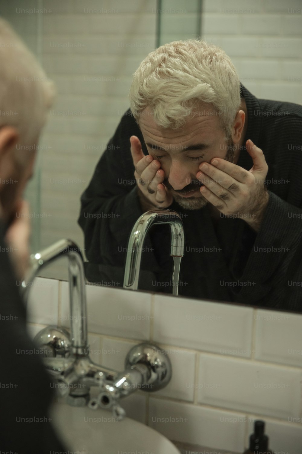 a man is looking at his reflection in the mirror
