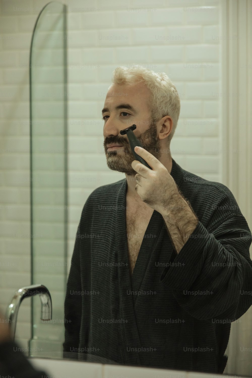 Ein Mann rasiert sich vor einem Spiegel das Gesicht