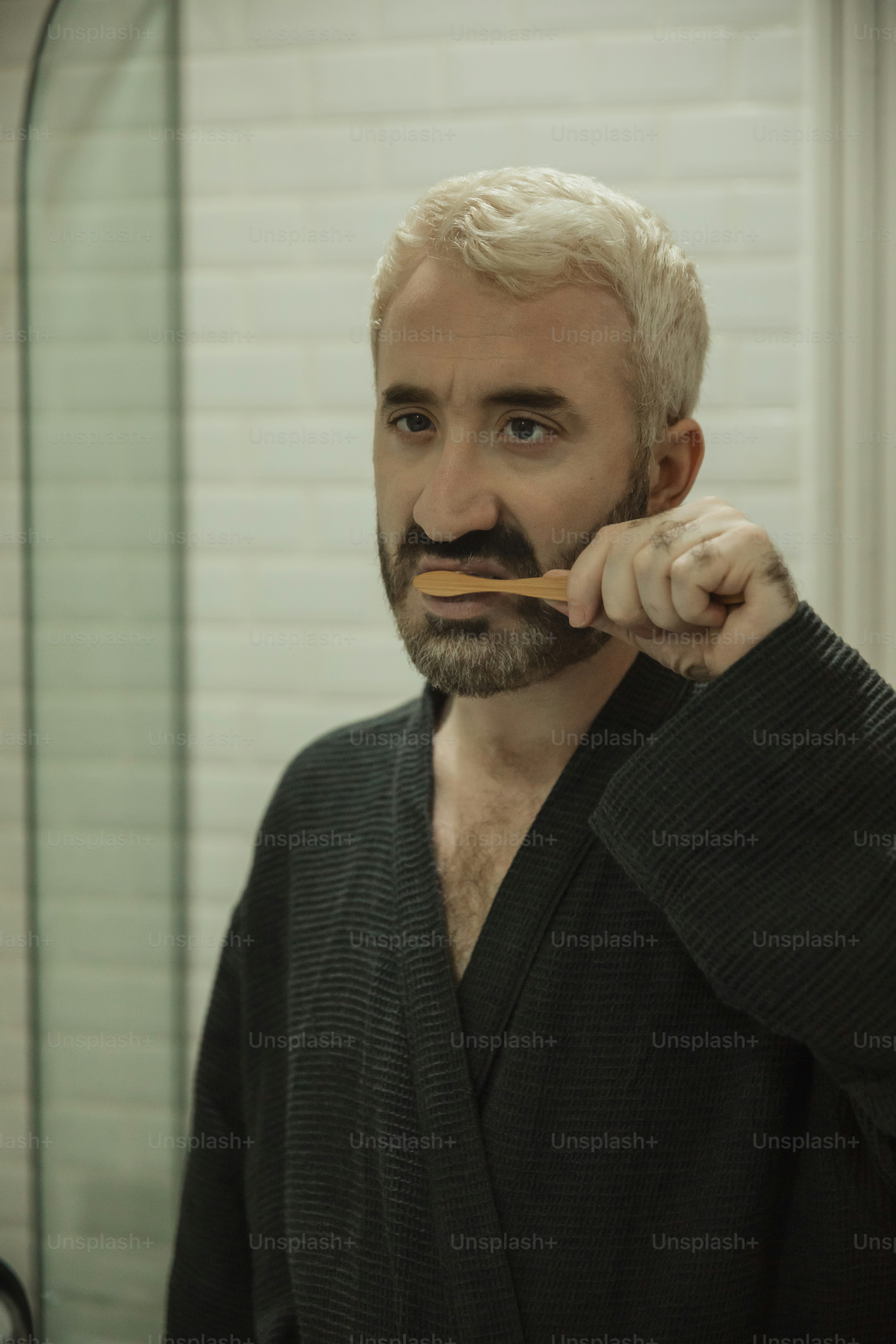 a man brushing his teeth with a wooden stick