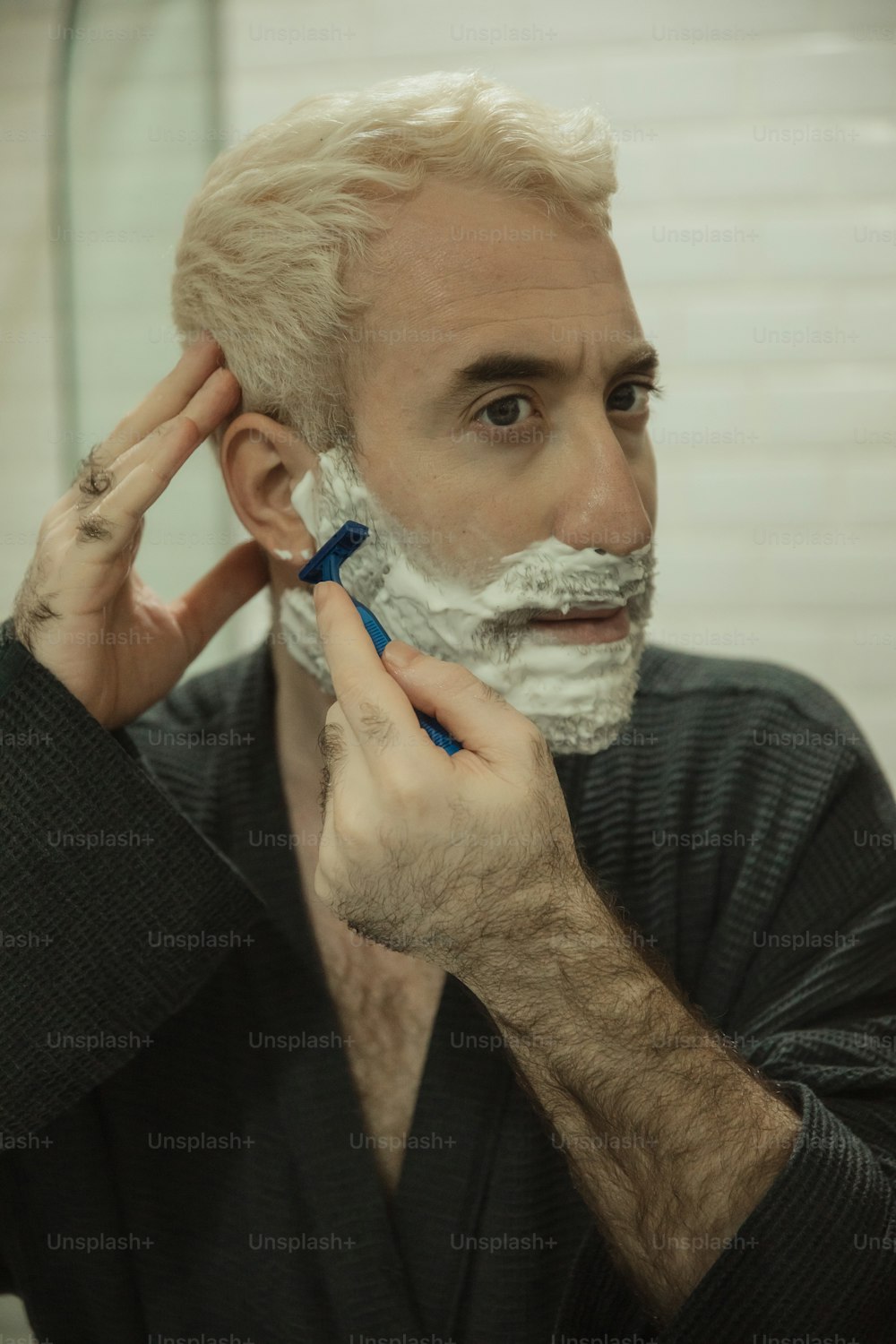 a man is shaving his face with a razor