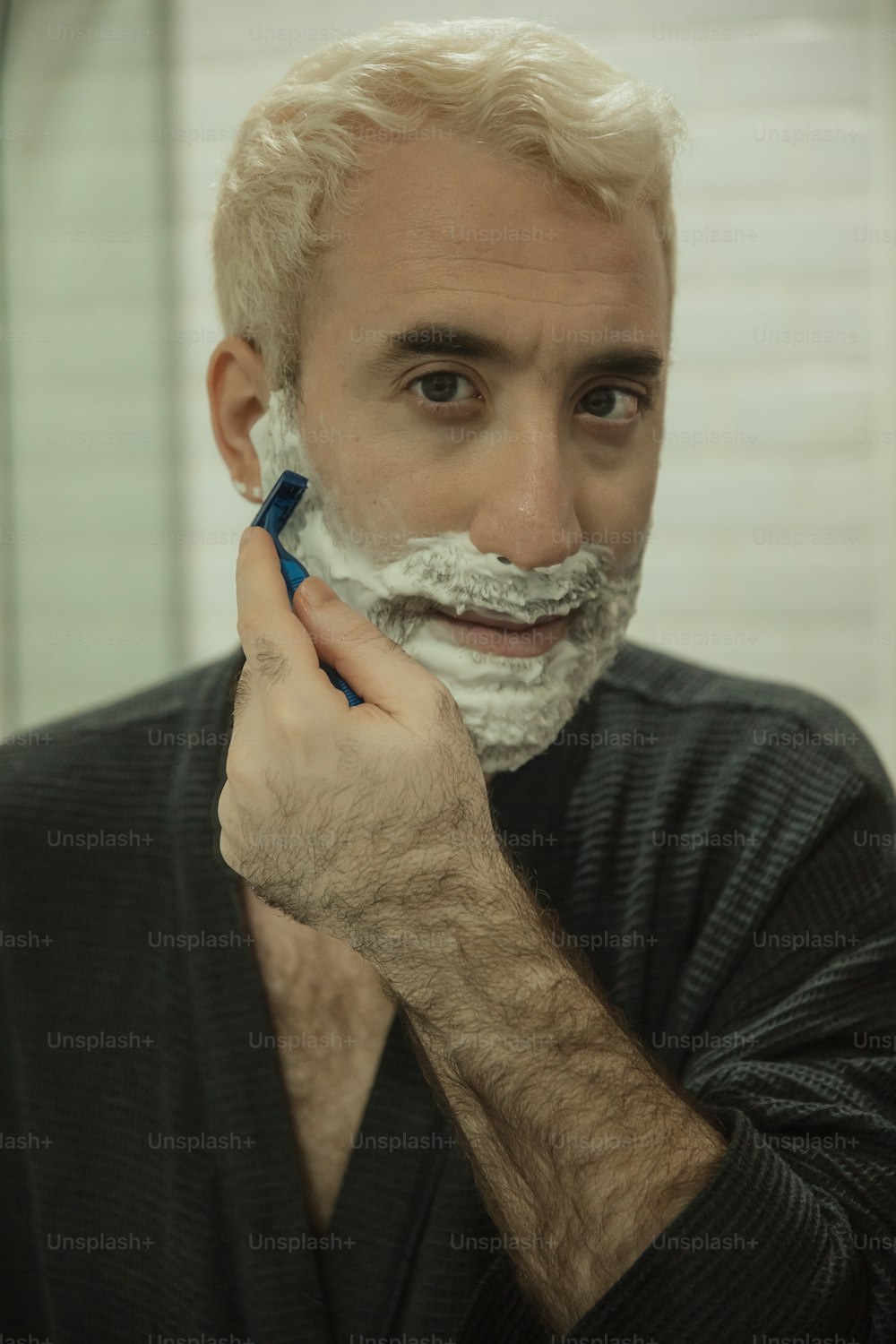 a man shaving his face with a razor