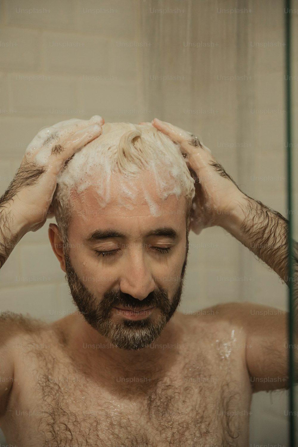 Ein Mann mit weißem Haar und Bart wäscht sich die Haare