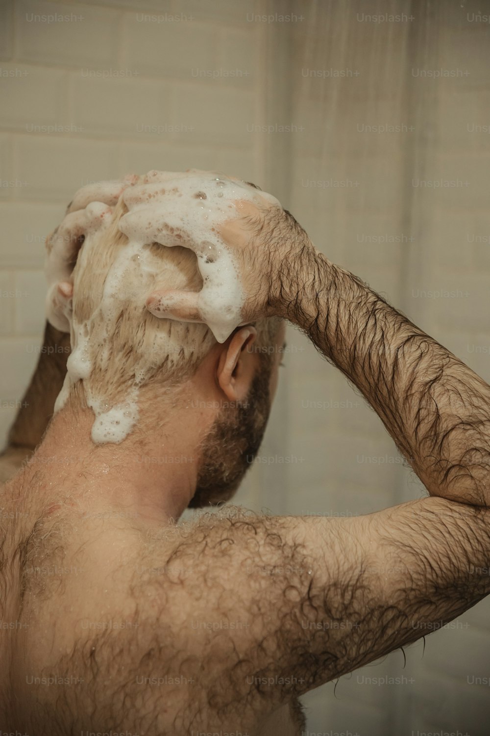 Un uomo si sta radendo i capelli sotto la doccia