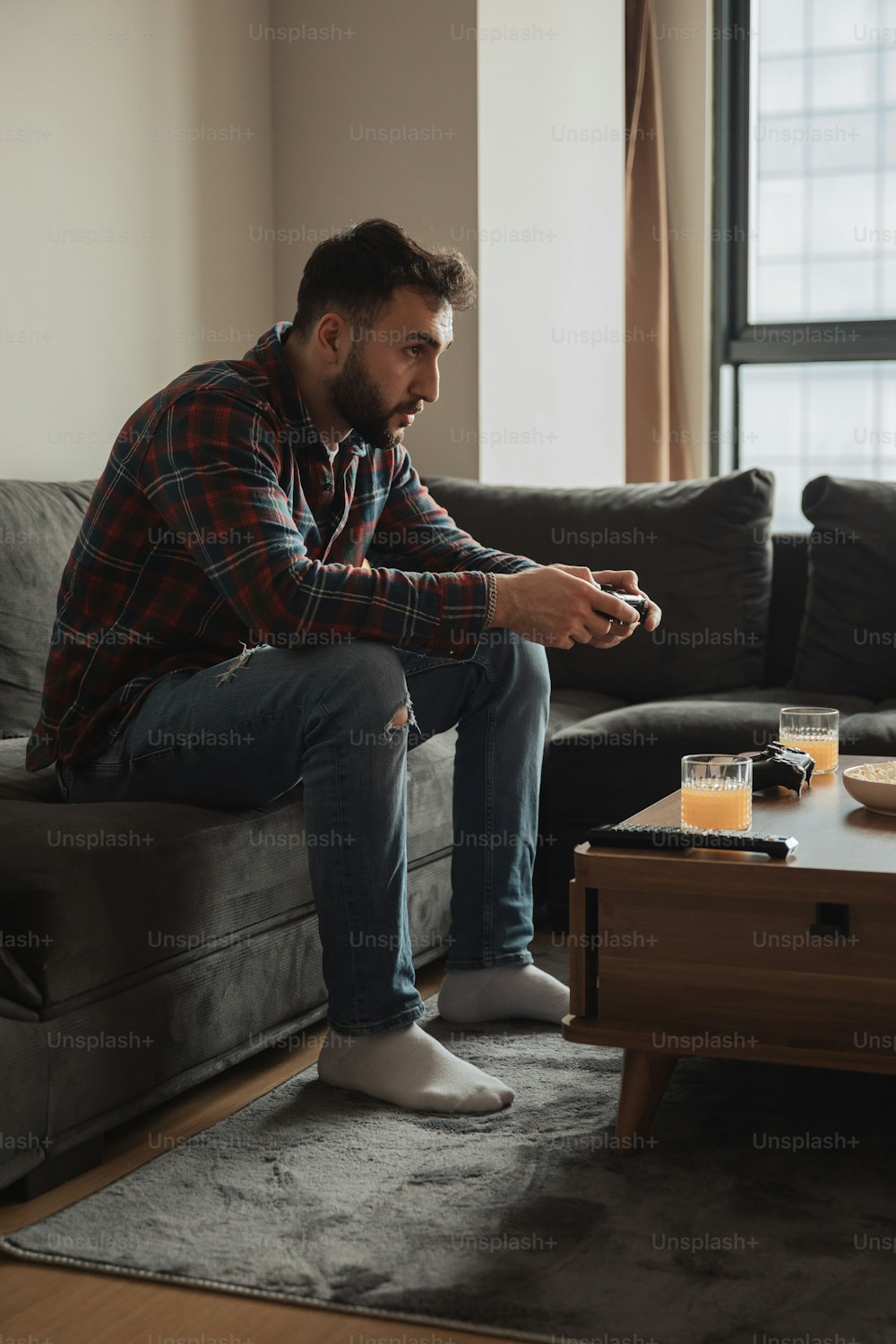 Ein Mann sitzt auf einer Couch und spielt ein Videospiel