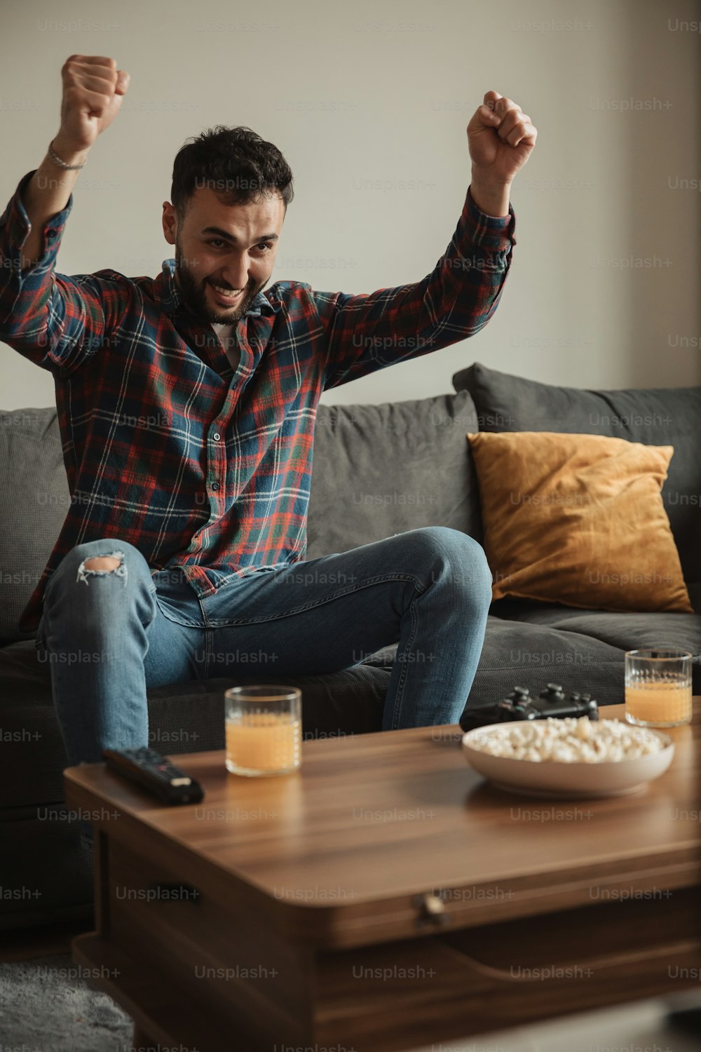 a man sitting on a couch with his arms in the air