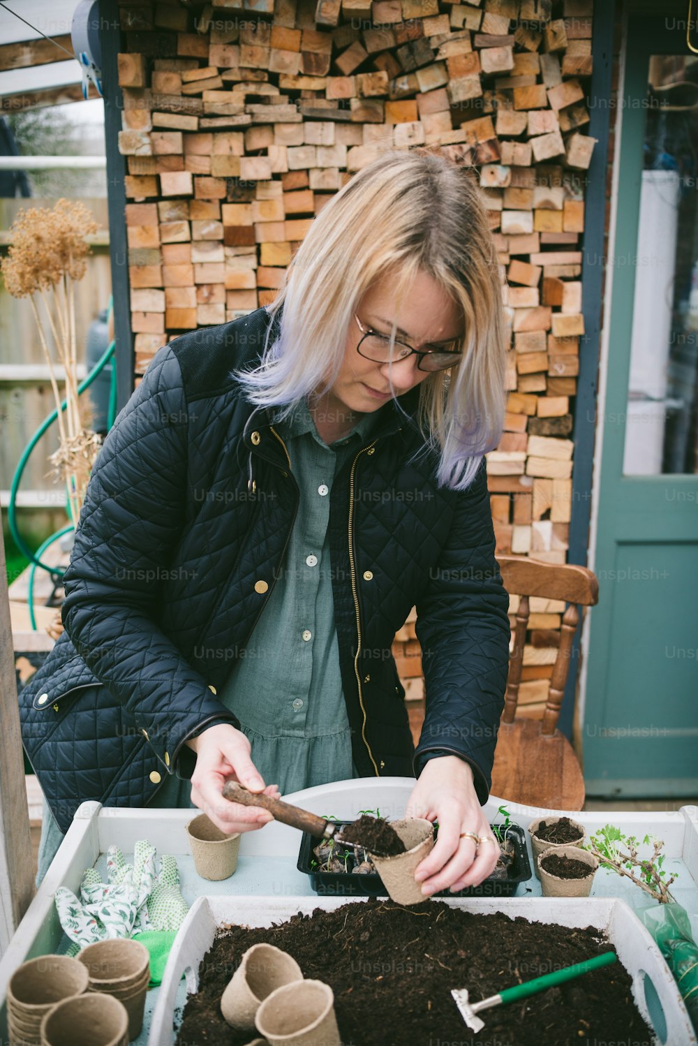 a woman in a black jacket and some dirt and plants