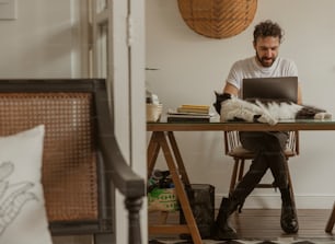 a man sitting at a desk with a cat on his lap