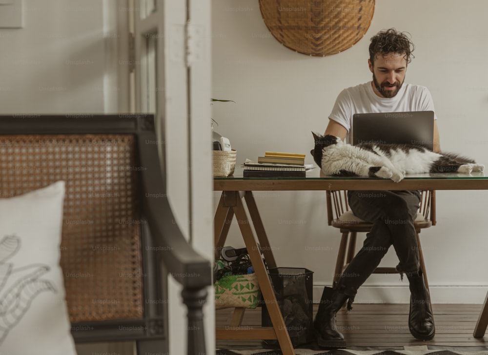 a man sitting at a desk with a cat on his lap