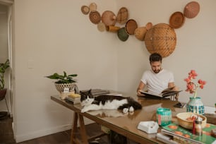 a man sitting at a table with a cat on his lap