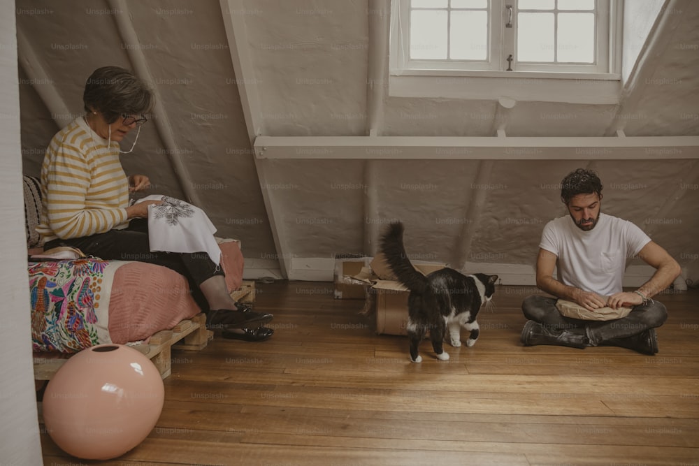 a man and a woman sitting on the floor with a cat