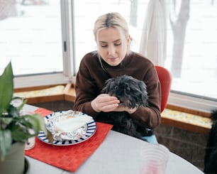 Una mujer sentada en una mesa con un pastel y un perro