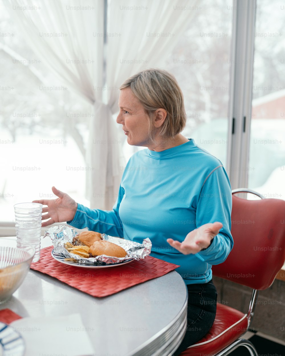 食べ物の皿を持ってテーブルに座ってい�る女性