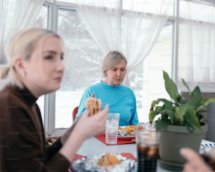 a group of women sitting around a table eating food