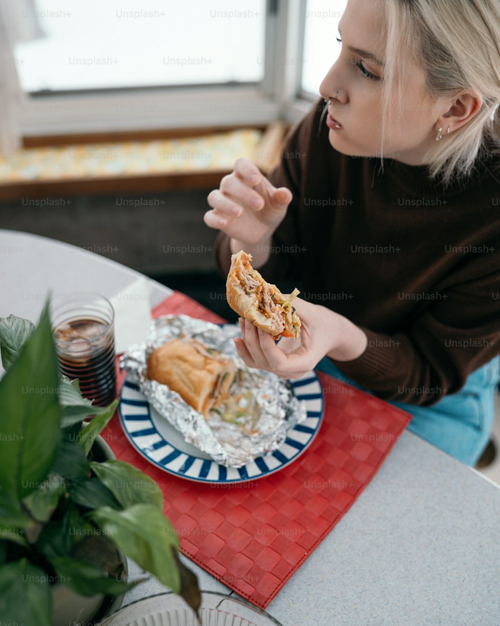 a woman sitting at a table eating a sandwich