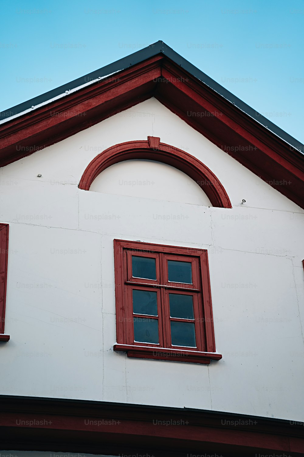 a white building with a red window and a black roof