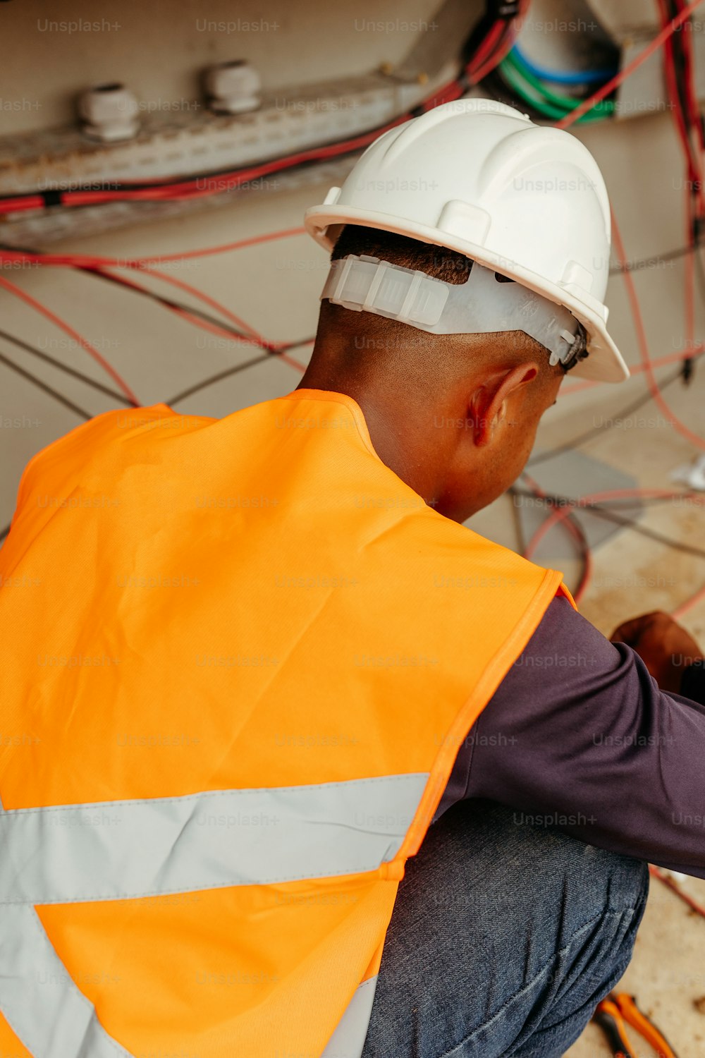 a man in an orange safety vest working on wires