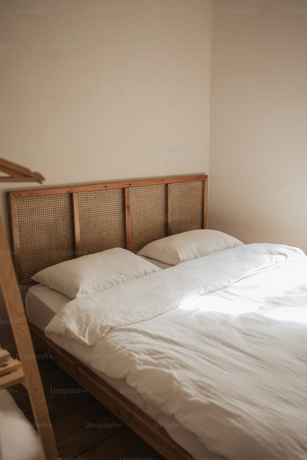 a bed with white sheets and pillows in a room