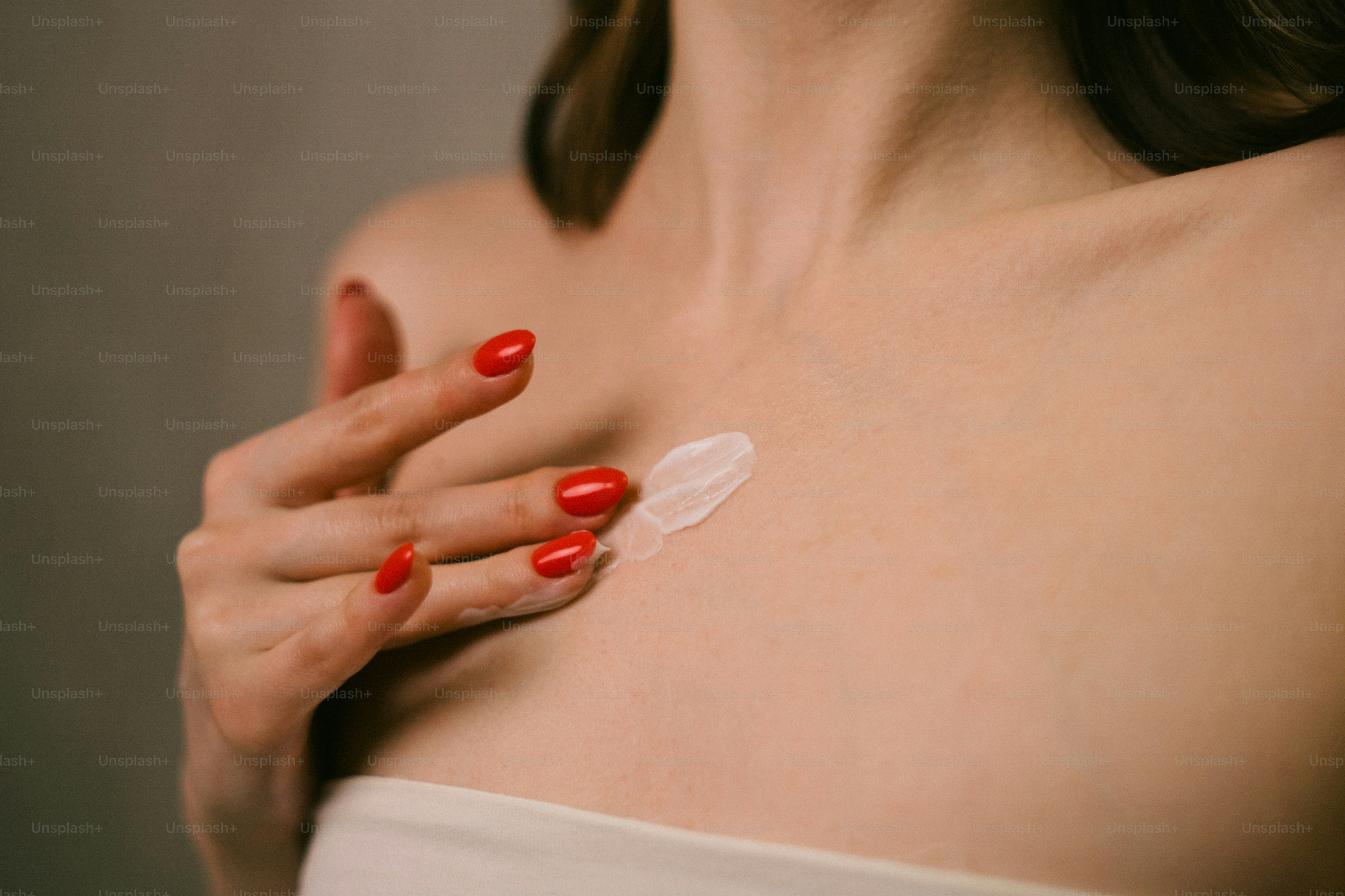 Eine Frau mit rotem Nagellack hält ein Stück Plastik in der Hand