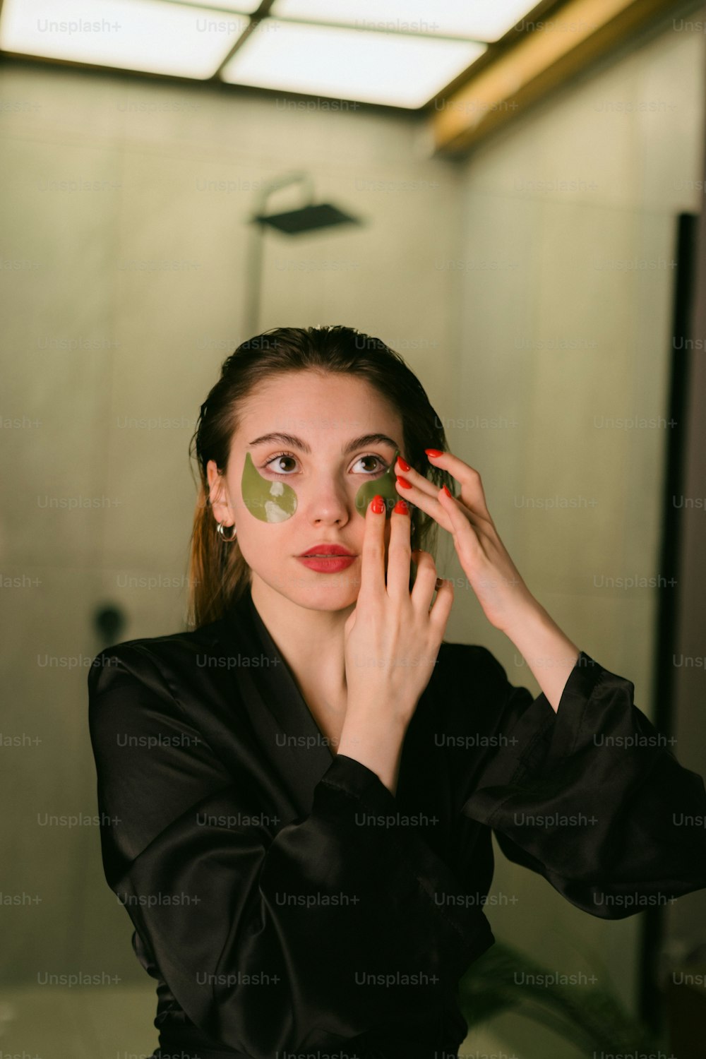 a woman putting on a green face mask