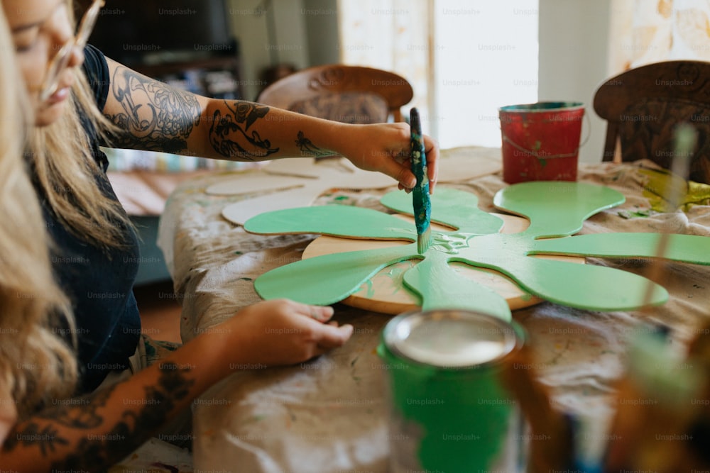 a woman painting a paper flower on a table