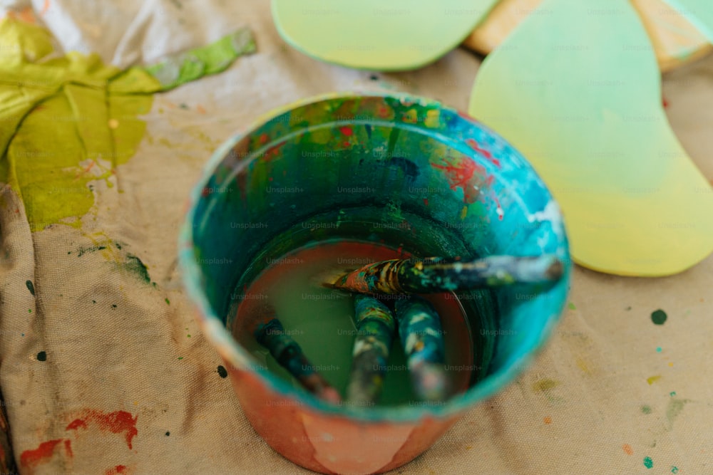 a cup filled with green liquid next to a leaf