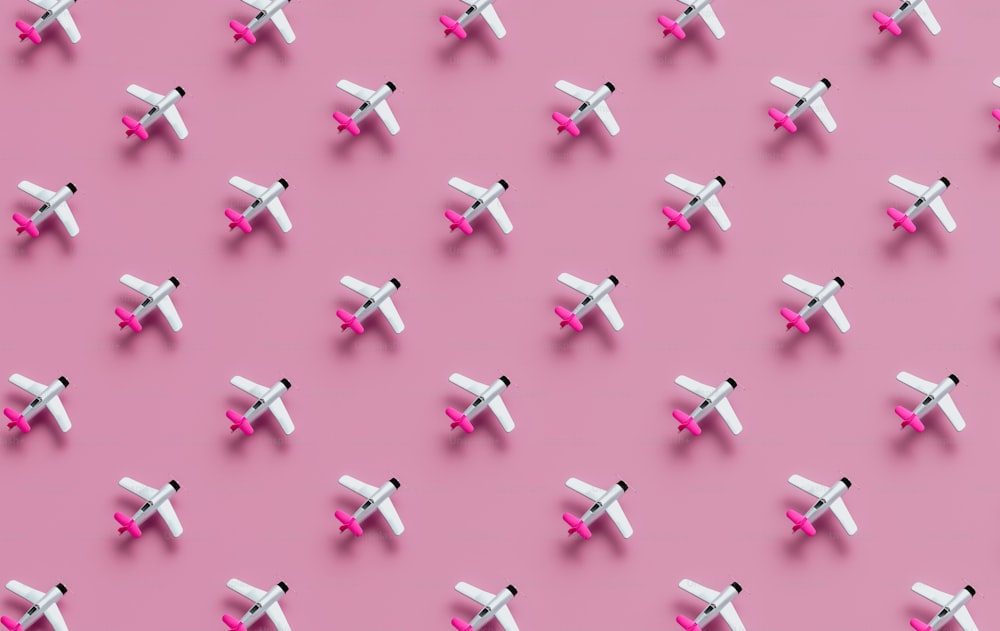 Un groupe de petits avions blancs sur fond rose