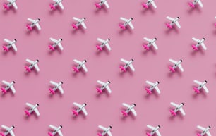 ピンクの背景に小さな白い飛行機のグループ
