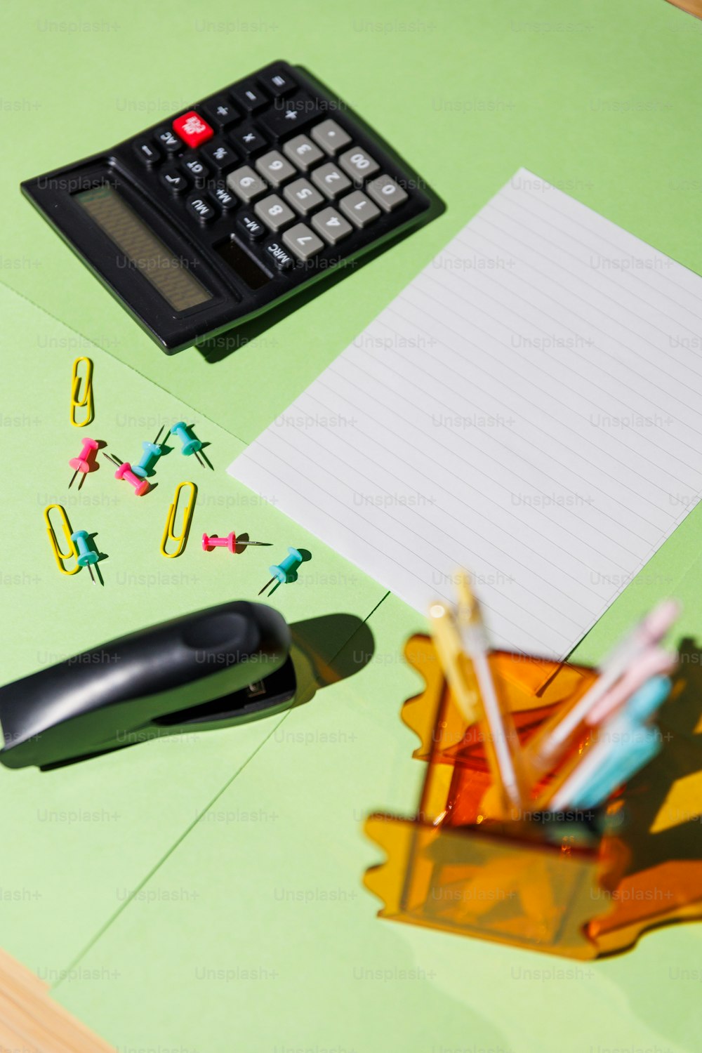 a desk with a calculator, pencils, and a notepad