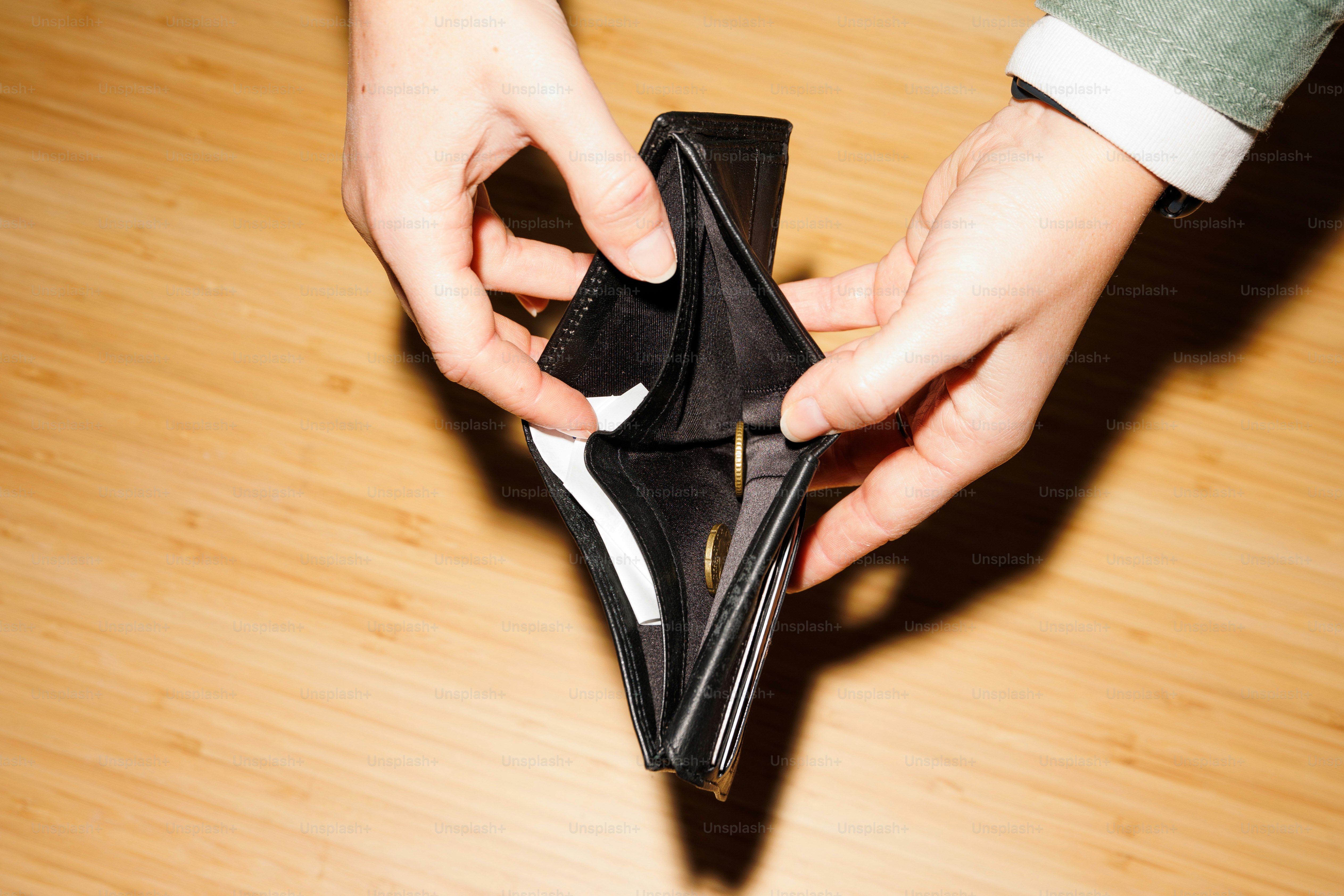 a person opening a wallet on a wooden floor