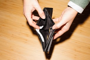 a person opening a wallet on a wooden floor