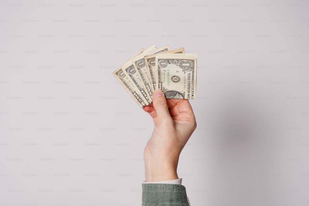 a person's hand holding a stack of money