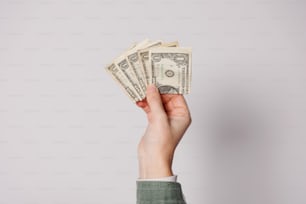 a person's hand holding a stack of money