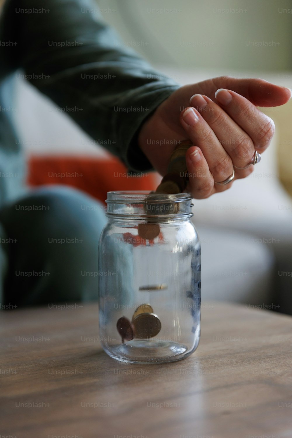 uma pessoa colocando uma moeda em um frasco de vidro