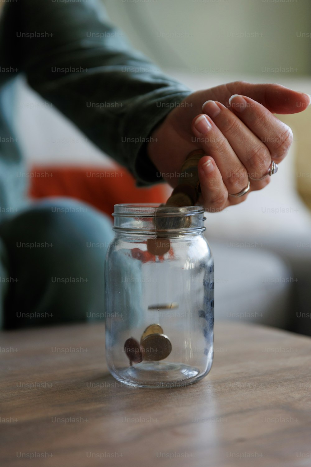 una persona che mette una moneta in un barattolo di vetro