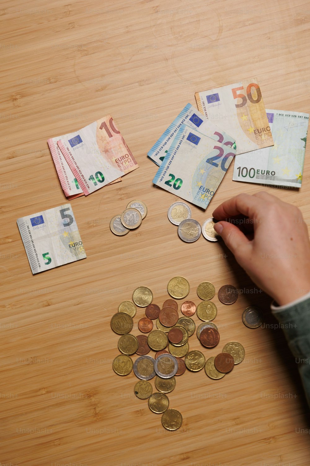 a person putting money into a pile on a table