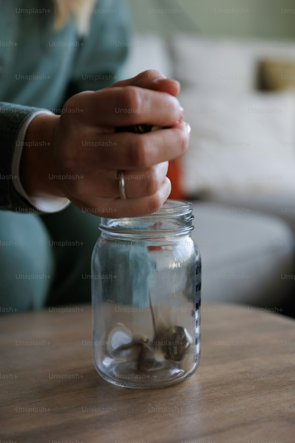 a person putting coins in a jar on a table