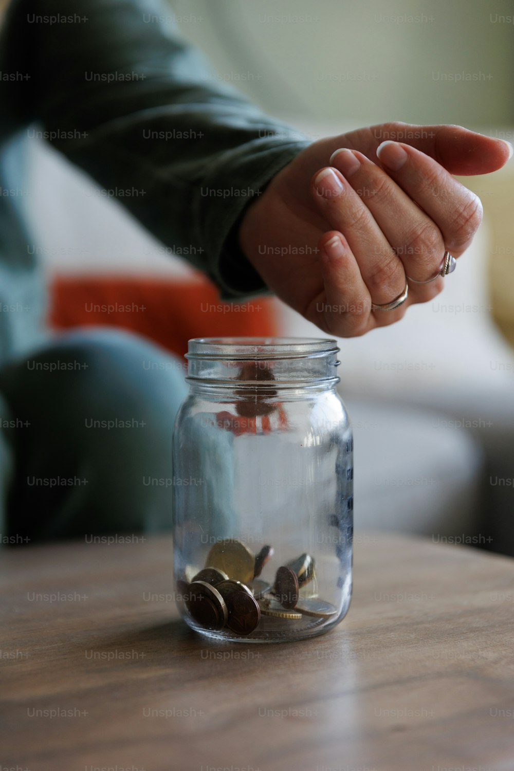 eine Person, die Münzen in ein Glasgefäß legt