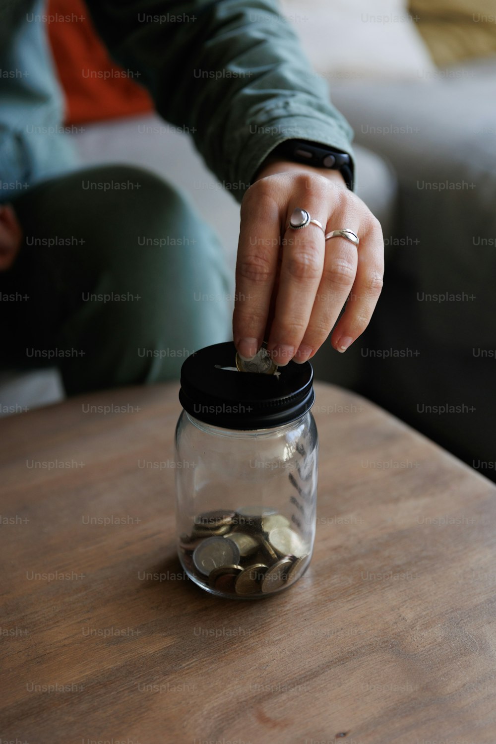 Eine Person, die Münzen in ein Glas auf einem Tisch legt