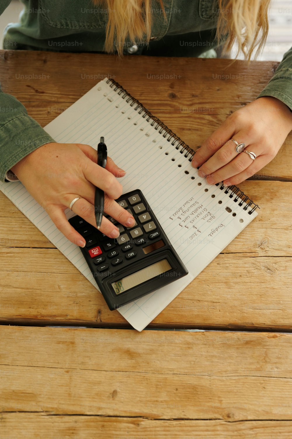 a woman using a calculator on top of a wooden table