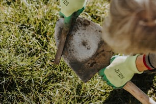 a person holding a shovel and digging in the grass