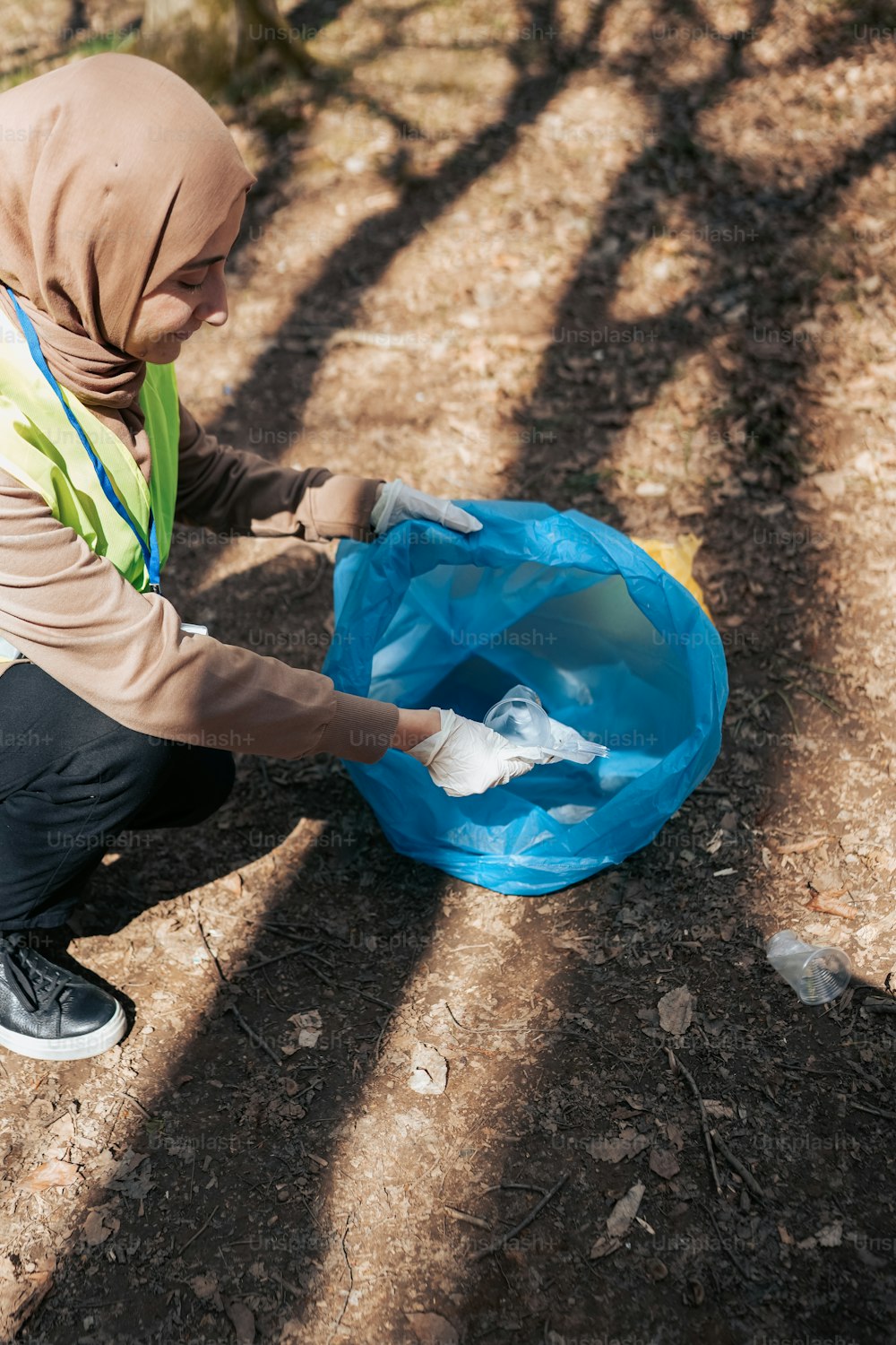 a woman in a hijab is cleaning a plastic bag