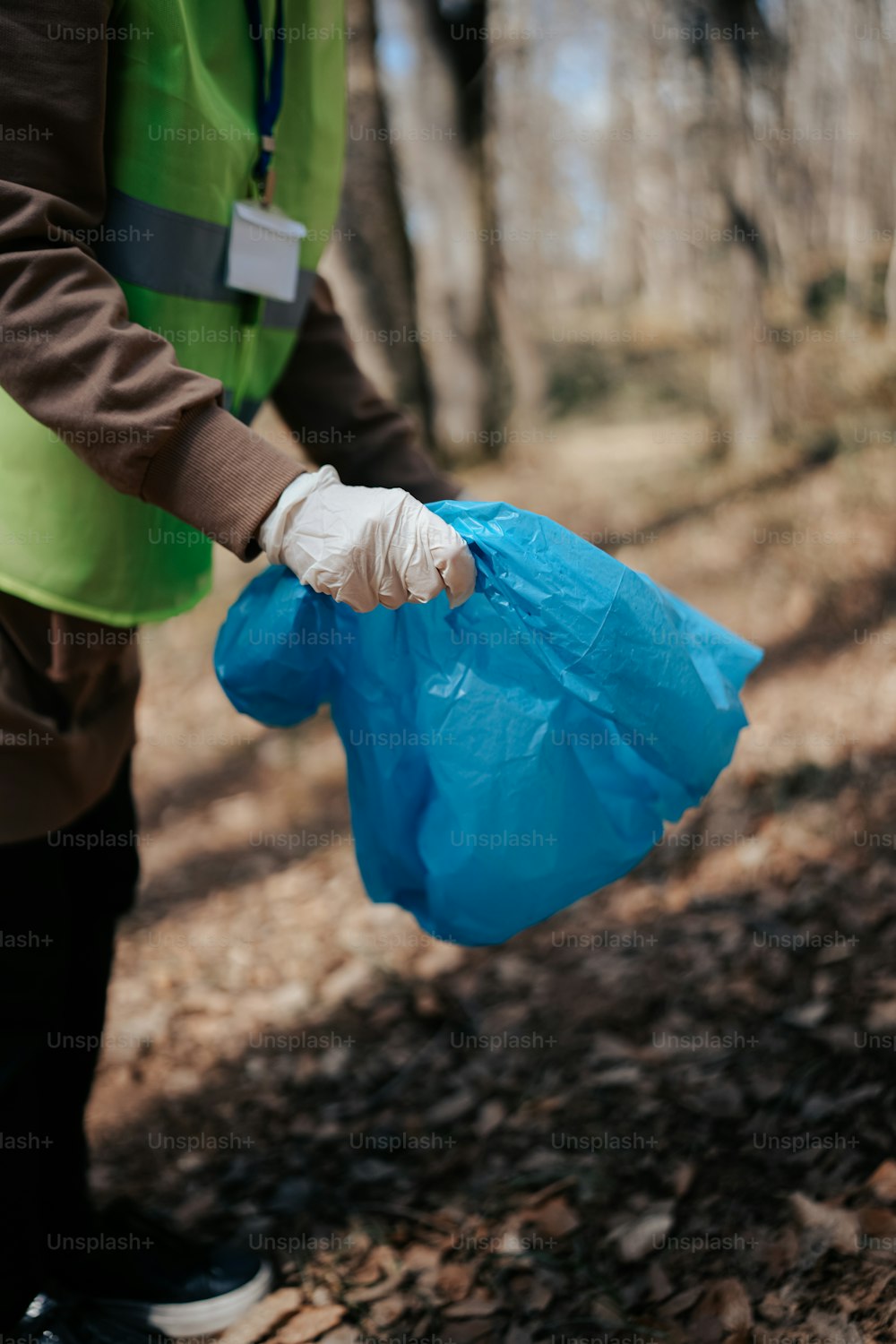 a person in a green vest holding a blue plastic bag