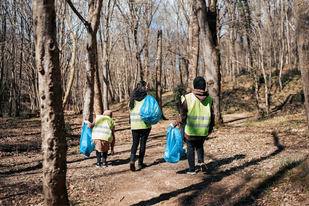three people walking in the woods carrying bags