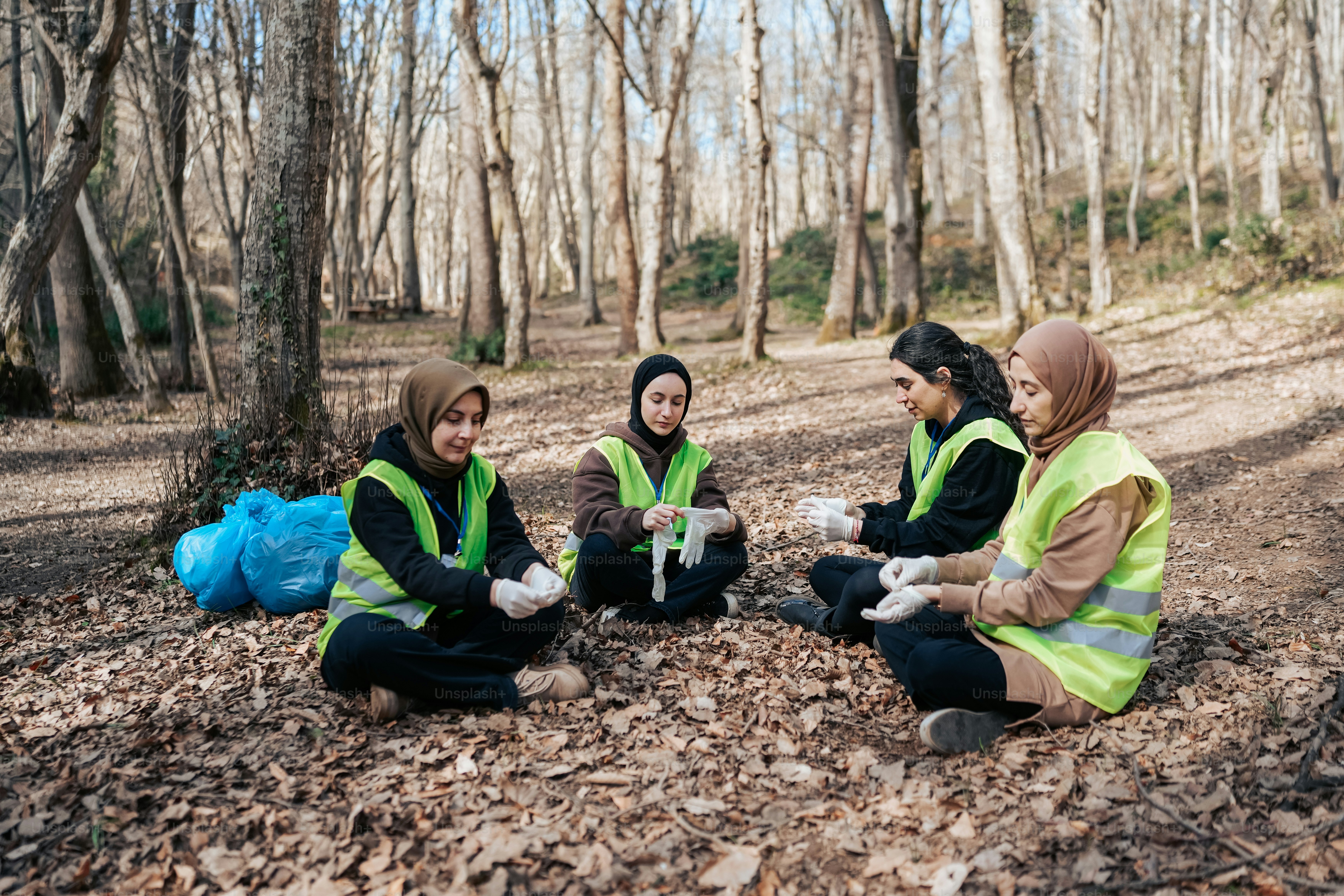 a group of people sitting on the ground in the woods